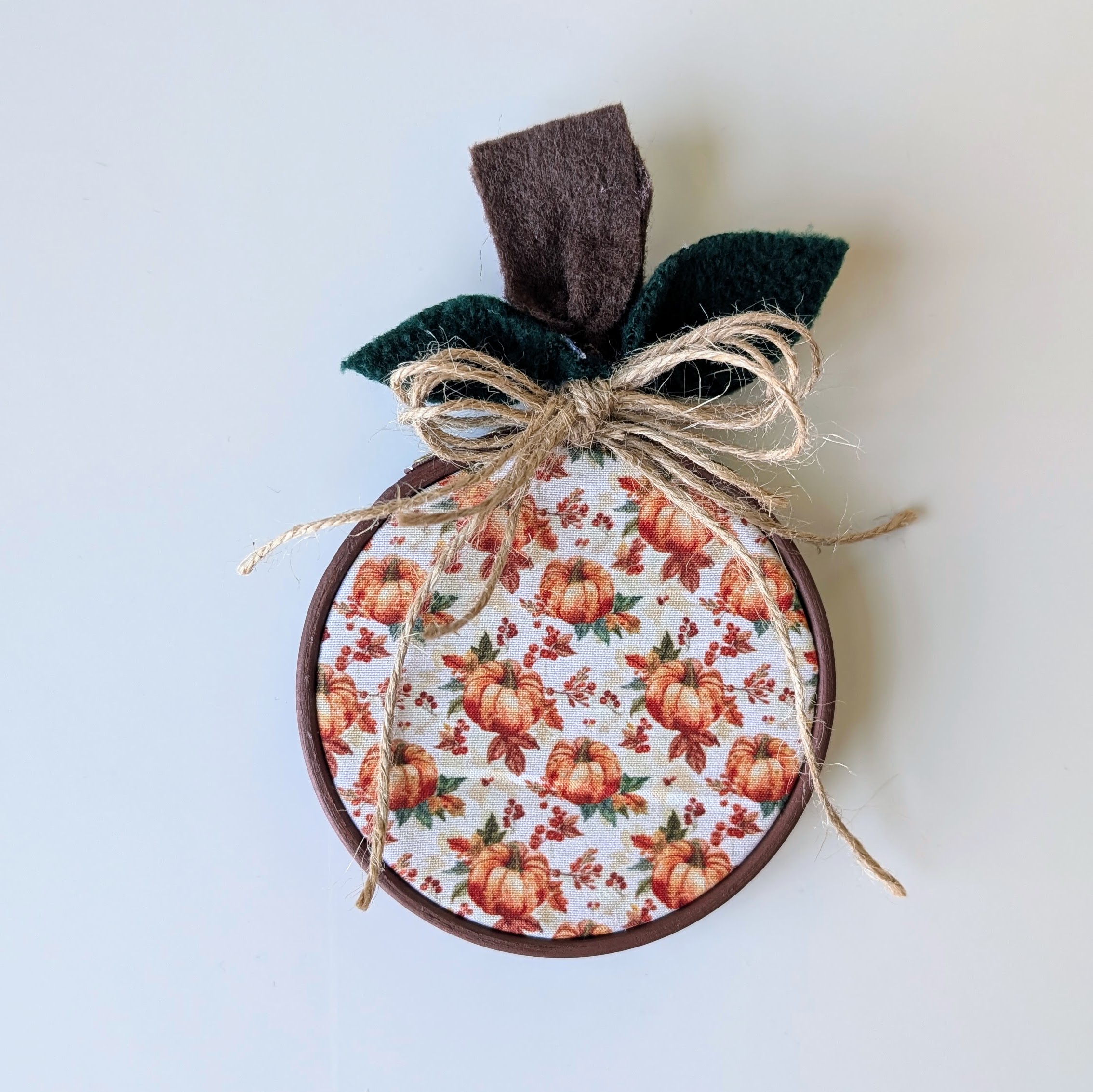 pumpkin fabric in a mini embroidery hoop that is tied with twine to mimic a pumpkin