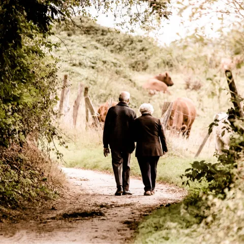 An elderly couple walking down a dirt path