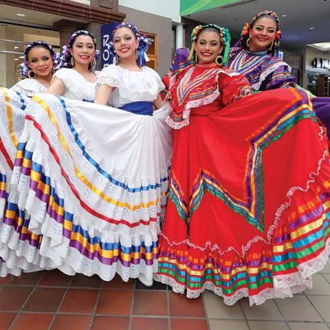 Ballet folklorico dancers wearing traditional brightly colored flowing dresses 