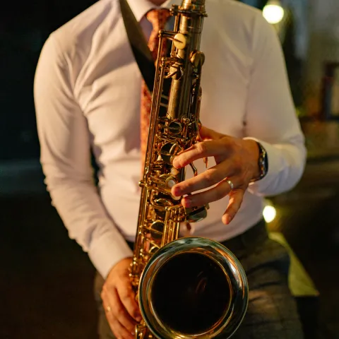 A man in a white button up shirt playing a saxophone 