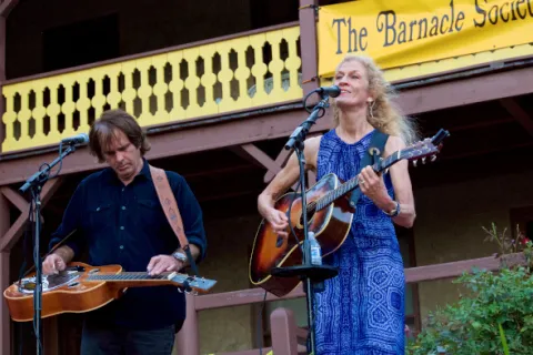 A man and woman on stage, each playing guitar while the woman sings