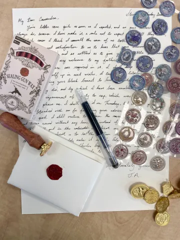 Letter writing materials and wax seal materials displayed on a desk.