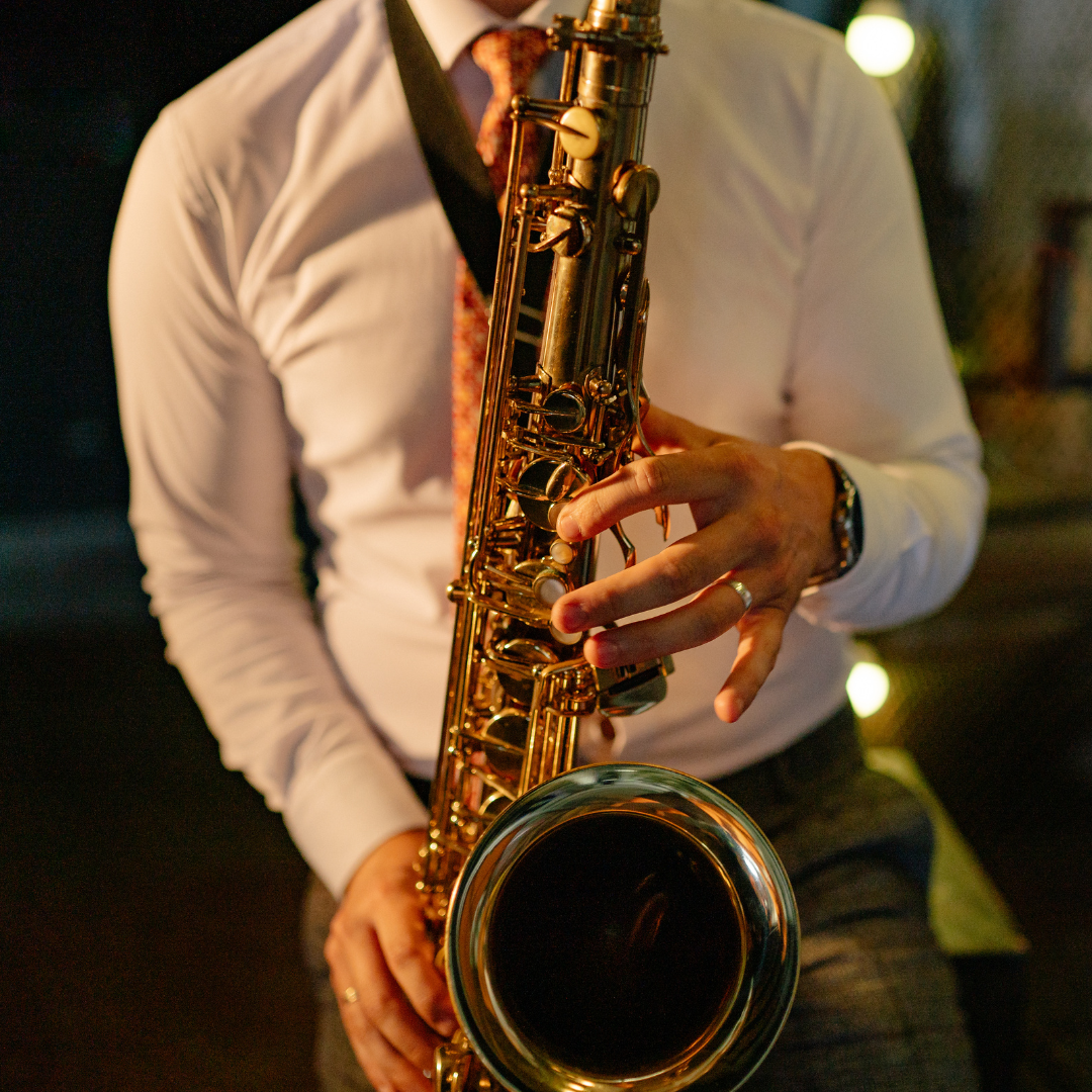 A man in a white button up shirt playing a saxophone 